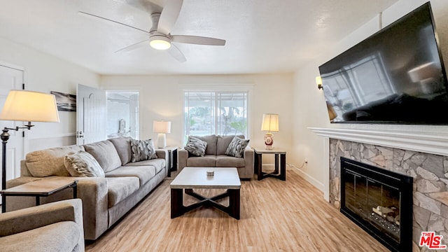 living room featuring a fireplace, light hardwood / wood-style floors, and ceiling fan