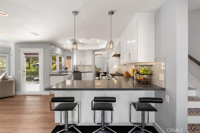 kitchen with decorative light fixtures, white cabinets, a kitchen bar, and kitchen peninsula