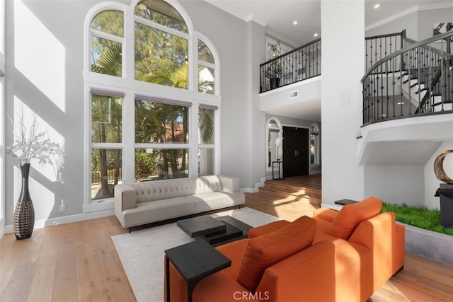 living room featuring a high ceiling, ornamental molding, and light hardwood / wood-style floors