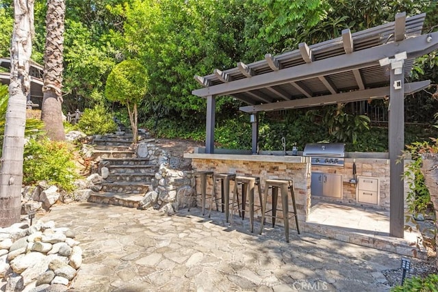 view of patio / terrace with exterior kitchen, area for grilling, an outdoor bar, and a pergola