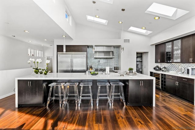 kitchen with a large island, stainless steel built in refrigerator, a breakfast bar area, and tasteful backsplash