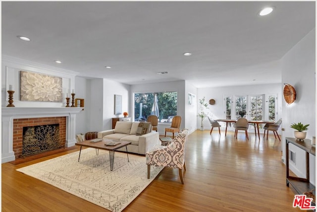 living room featuring a brick fireplace and light hardwood / wood-style flooring