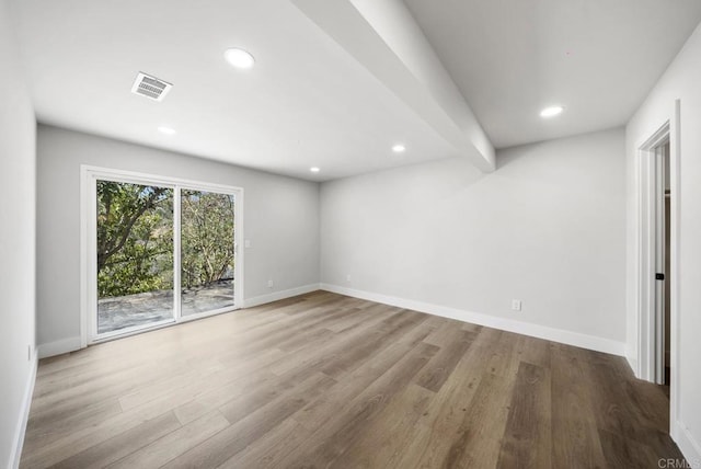 unfurnished room with light hardwood / wood-style floors and beam ceiling