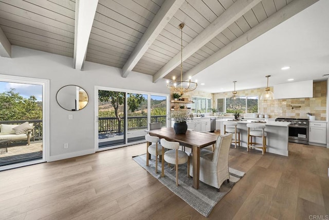 dining area with sink, an inviting chandelier, vaulted ceiling with beams, and light hardwood / wood-style flooring