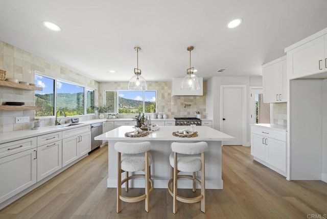 kitchen with stainless steel appliances, sink, white cabinets, backsplash, and pendant lighting