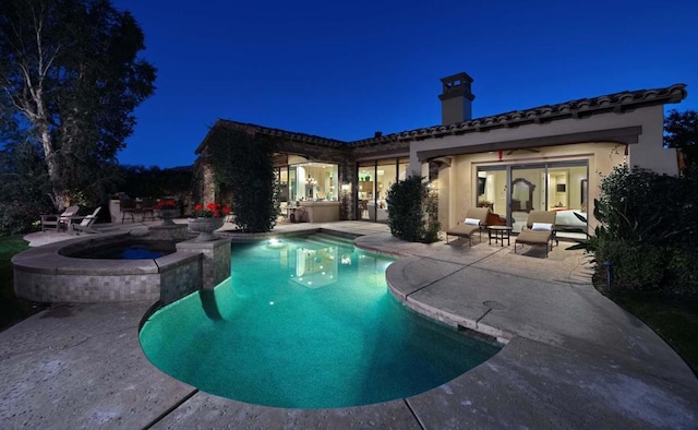 pool at twilight featuring a patio area and an in ground hot tub