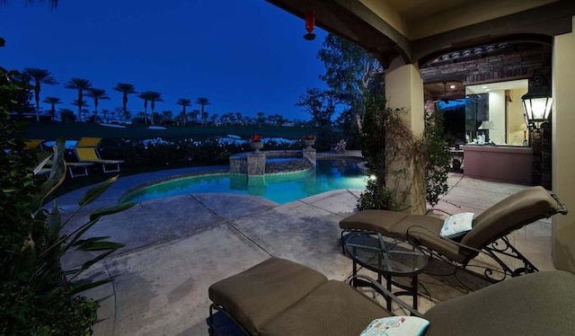 pool at twilight featuring a patio area and an in ground hot tub