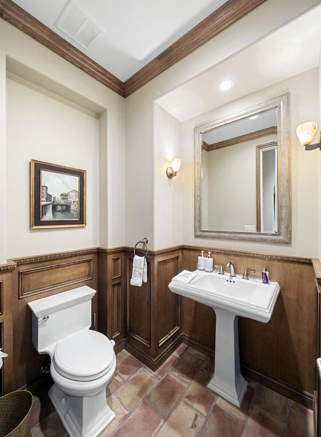 bathroom featuring toilet, ornamental molding, and sink