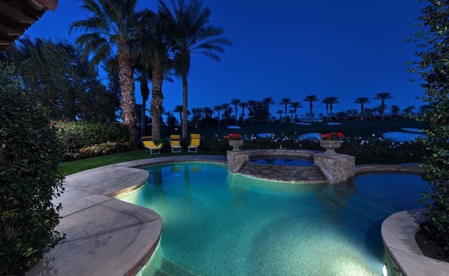 pool at night featuring an in ground hot tub