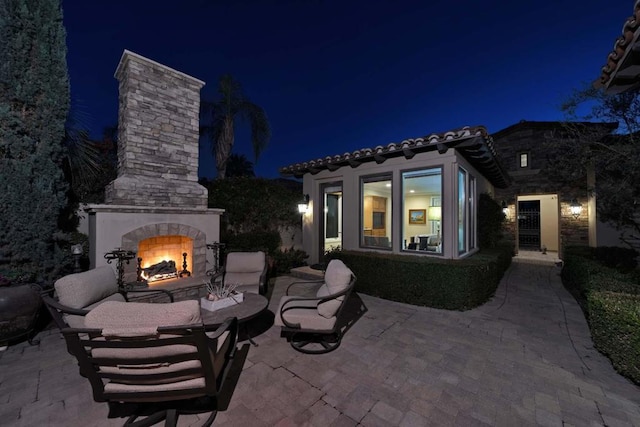 patio at twilight featuring an outdoor stone fireplace