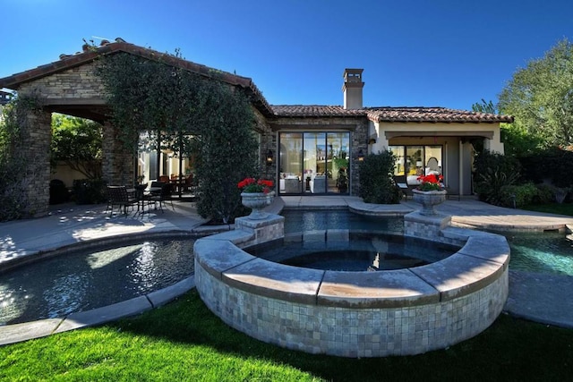 rear view of house featuring a patio area and a pool with hot tub