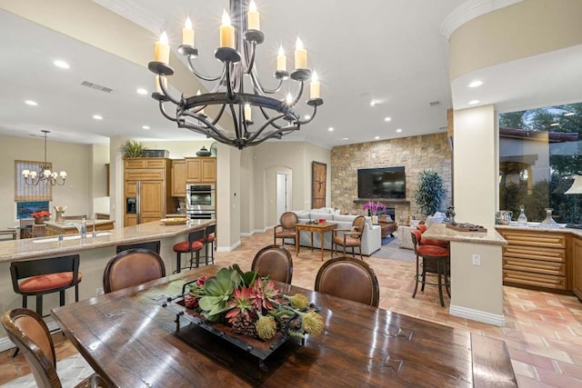 dining space with crown molding, a fireplace, a chandelier, and sink