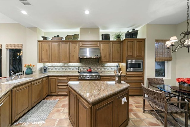 kitchen with stainless steel microwave, sink, hanging light fixtures, tasteful backsplash, and stove