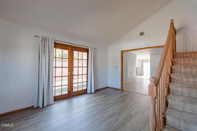 unfurnished room with french doors, light hardwood / wood-style flooring, and vaulted ceiling