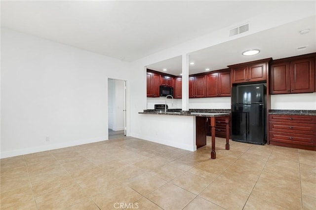 kitchen with kitchen peninsula, light tile patterned floors, dark stone countertops, and black appliances