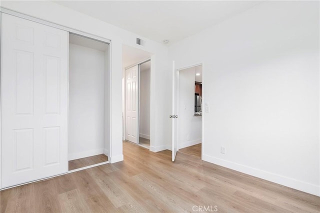 unfurnished bedroom with light hardwood / wood-style flooring and a closet