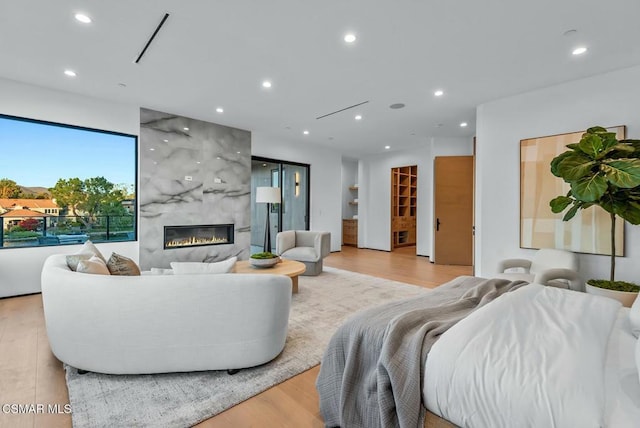 living room with light wood-type flooring and a tiled fireplace