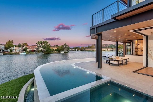 pool at dusk featuring an in ground hot tub, an outdoor living space, a patio, and a water view