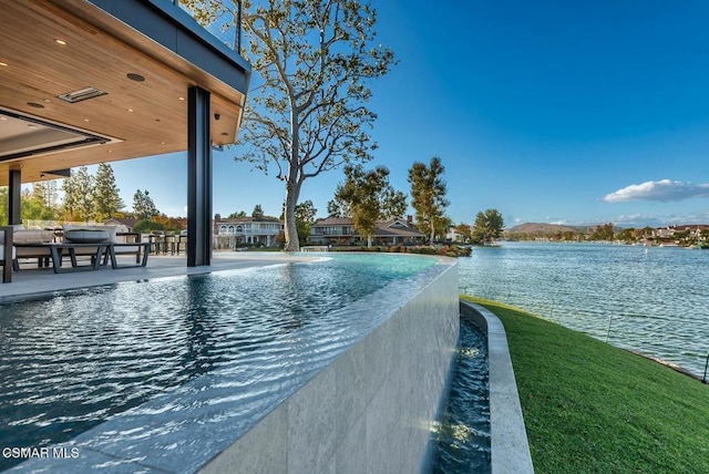 view of swimming pool with pool water feature, a water view, and a patio