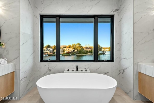 bathroom featuring a tub, a water view, and a healthy amount of sunlight