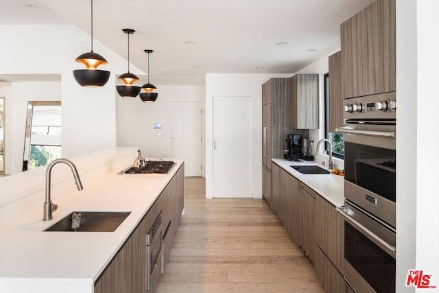 kitchen with stainless steel appliances, a wealth of natural light, sink, and pendant lighting