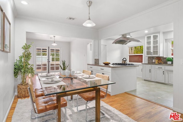 dining room with ornamental molding, light hardwood / wood-style floors, and french doors