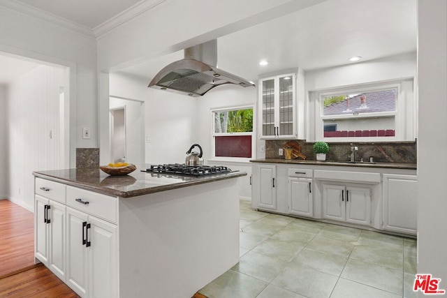 kitchen featuring white cabinetry, island range hood, stainless steel gas cooktop, and decorative backsplash