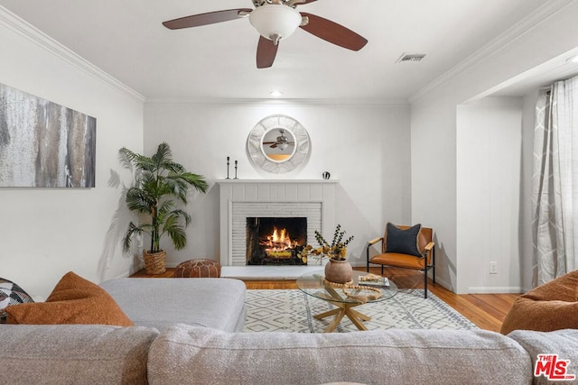 living room with ornamental molding, a fireplace, and light hardwood / wood-style flooring