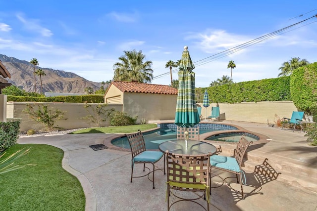 view of patio featuring a mountain view and an in ground hot tub