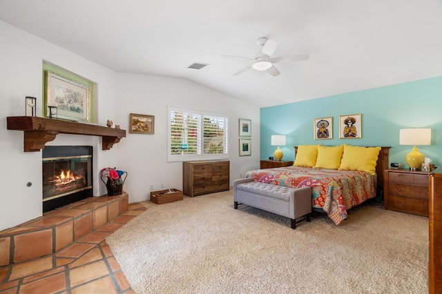 bedroom featuring ceiling fan, light tile patterned flooring, a tiled fireplace, and vaulted ceiling