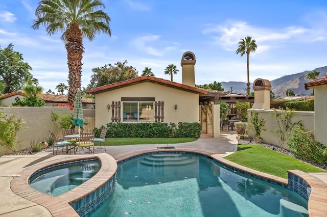 rear view of house featuring a patio area, a mountain view, and a swimming pool with hot tub