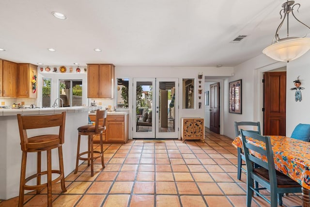 kitchen featuring pendant lighting, a breakfast bar, light tile patterned floors, tasteful backsplash, and tile counters