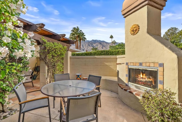 view of patio featuring a mountain view and exterior fireplace