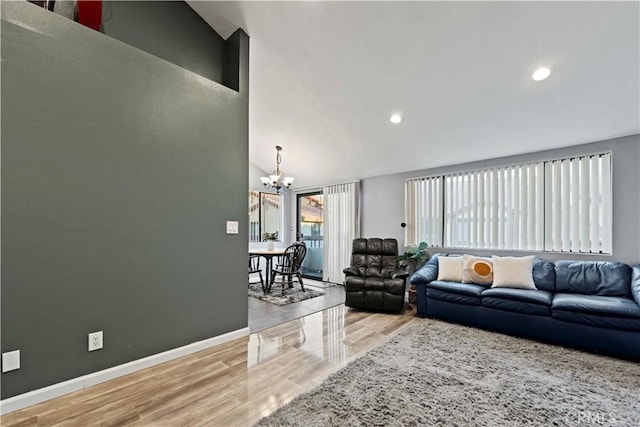 living room featuring lofted ceiling, hardwood / wood-style floors, and a notable chandelier