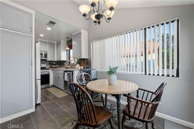 tiled dining space with sink, vaulted ceiling, and a chandelier