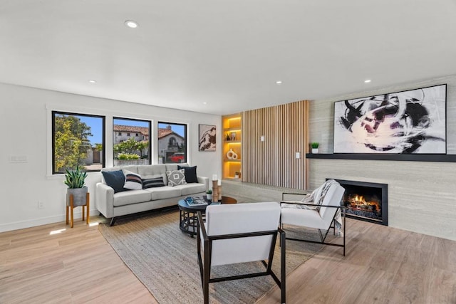 living room with a large fireplace and light hardwood / wood-style flooring