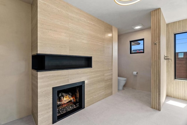 bathroom with a tile fireplace, tile patterned floors, and toilet