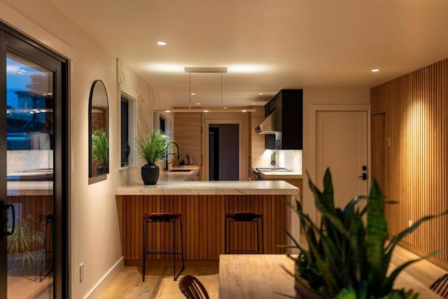 kitchen with a breakfast bar, kitchen peninsula, and light hardwood / wood-style flooring