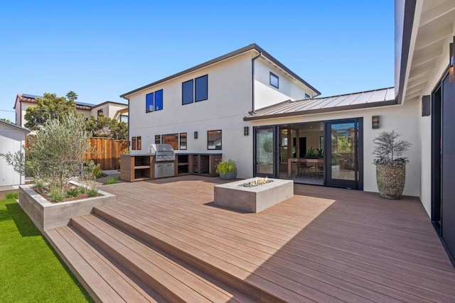 wooden terrace with area for grilling, an outdoor fire pit, and a grill