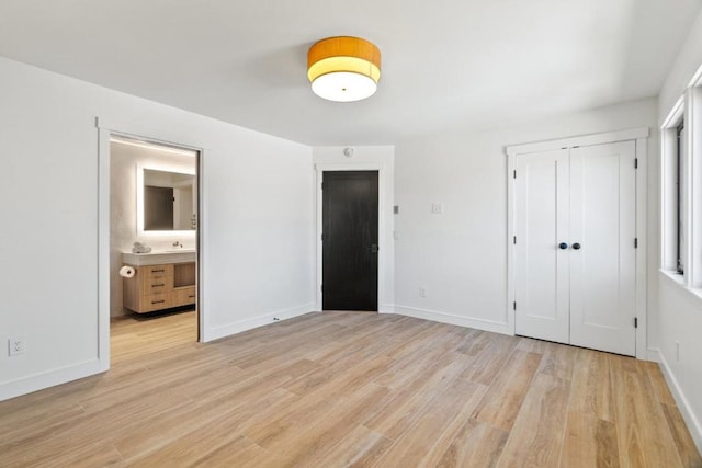 unfurnished bedroom with connected bathroom, a closet, and light hardwood / wood-style floors