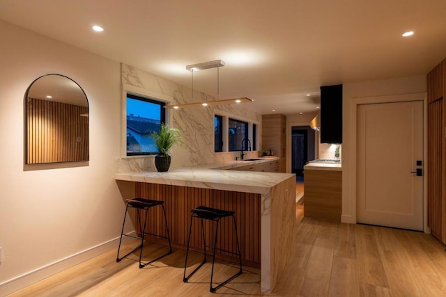 bar featuring decorative backsplash, sink, and light wood-type flooring