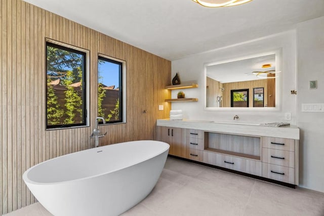 bathroom with concrete flooring, a bath, vanity, and wood walls