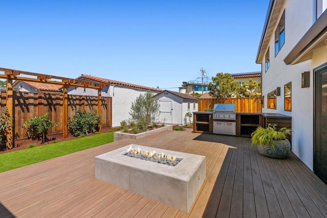 wooden deck featuring an outdoor fire pit and a grill