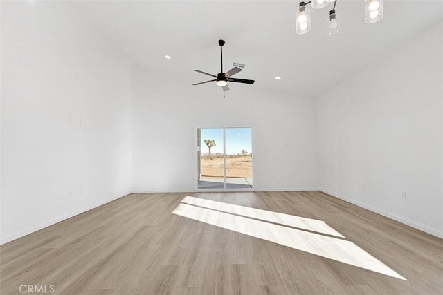 unfurnished room with ceiling fan, a towering ceiling, and light hardwood / wood-style floors