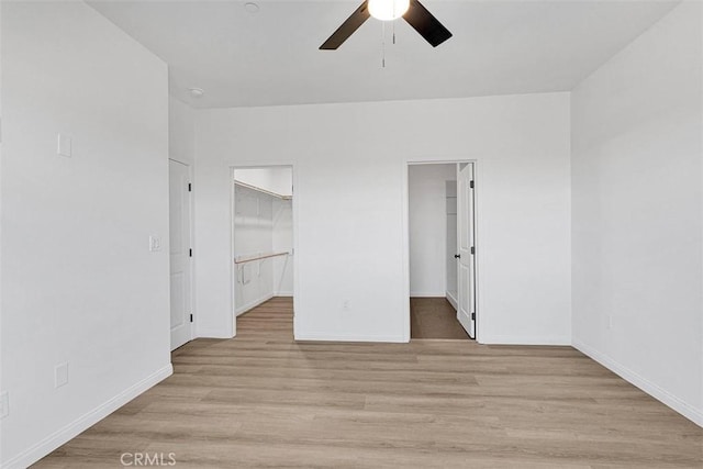 unfurnished bedroom featuring a walk in closet, a closet, and ceiling fan