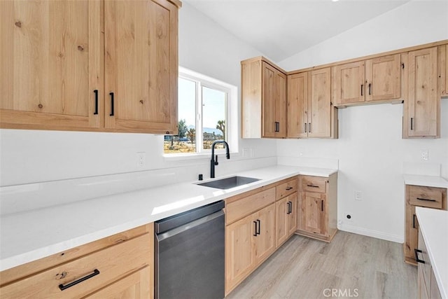 kitchen featuring light brown cabinets, lofted ceiling, sink, stainless steel dishwasher, and light hardwood / wood-style floors