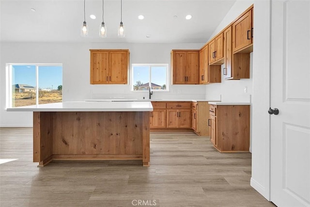 kitchen featuring a kitchen island, a healthy amount of sunlight, decorative light fixtures, and light wood-type flooring