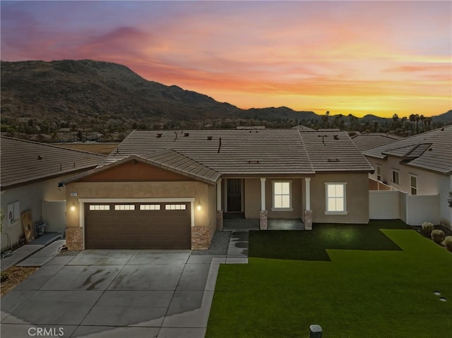 view of front of property with a garage, a mountain view, and a yard