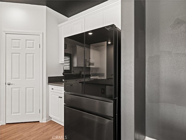 kitchen featuring white cabinetry, light hardwood / wood-style flooring, and black fridge