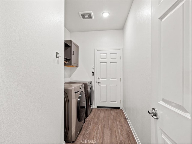 laundry area with light hardwood / wood-style floors, cabinets, and washing machine and clothes dryer